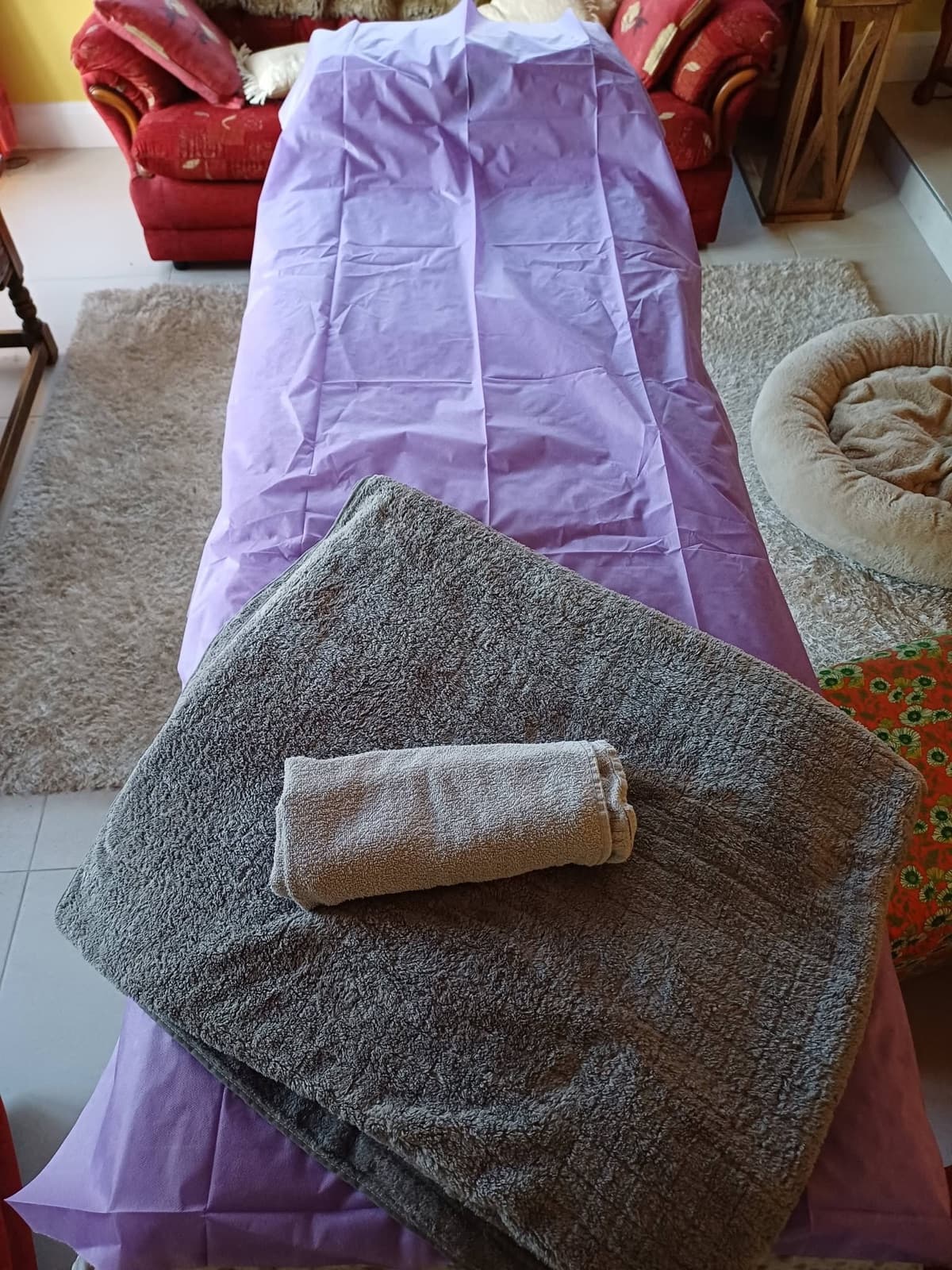 Massage table with fresh lilac covers and towels set up in a customer's living room